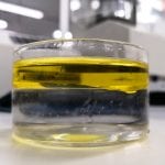 Interface between water and oil, two immiscible liquids, inside a glass beaker in a scientific laboratory