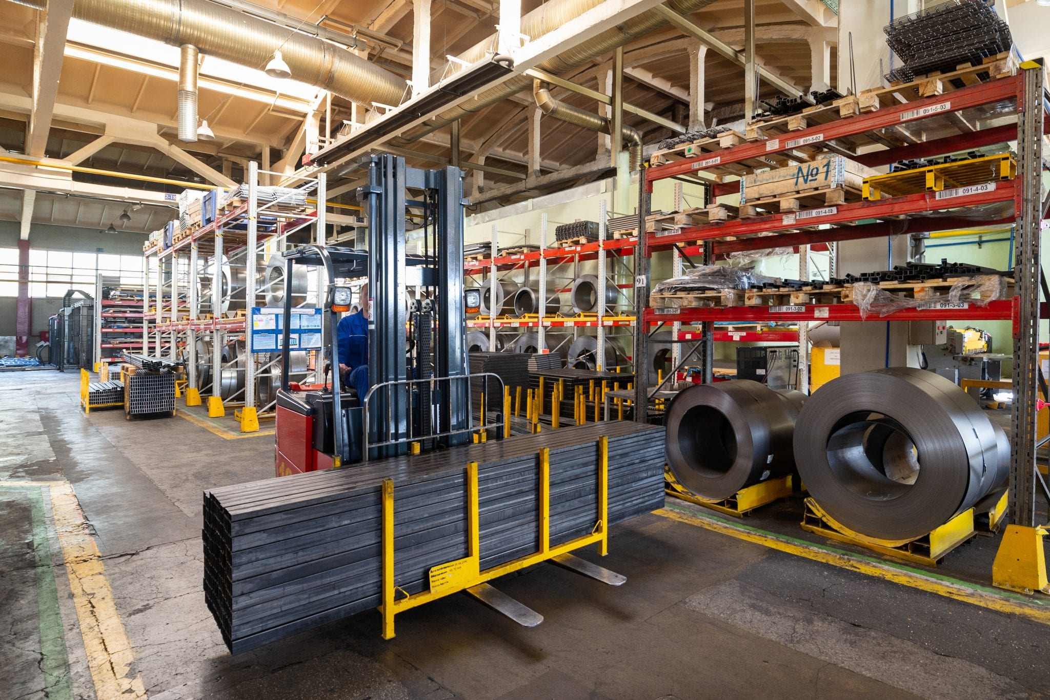 Factory stock wire. Wire rolled into coils lie on multi-tiered racks.